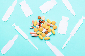 assorted drugs and pills near medicaments isolated over blue background. medication concept. syringe,vial,ampoule shapes made paper