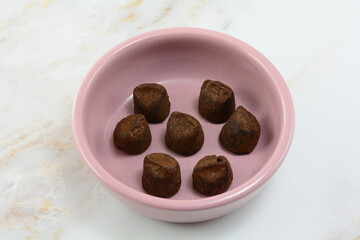Cocoa dusted chocolate truffles treat in small pink snack bowl on table