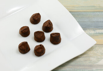 Cocoa dusted chocolate truffles treat on white dessert plate on table