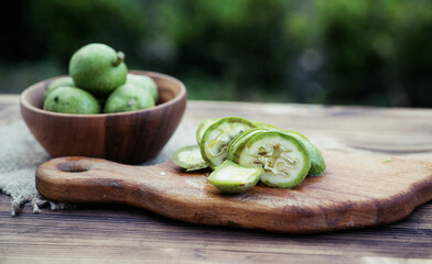 healthy food. Walnuts, cut into slices, are scattered on a cutting board. Old vintage table and whole unripe walnut fruit