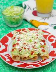 Tacos fritos mexicanos de pollo con crema y queso acompañados de jugo de naranja