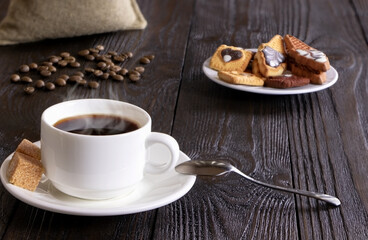 A cup of coffee and cake on a wooden background. Morning hot coffee and pastry on a wooden table. Coffee beans. A white coffee cup and cane sugar. Steam.Espresso.