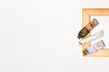 Art materials such as tubes of oil paints and a stretcher lie on a white background. View from above.