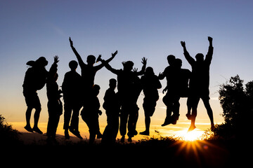 Fototapeta na wymiar Group many peoples silhouettes jumping in sunset on mountain