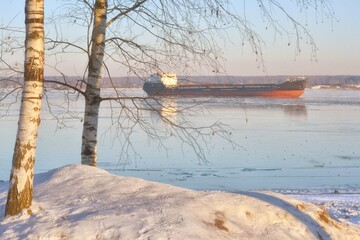 Natural winter ice landscape in the cargo port. Cargo ship in sea full of ice in winter.
