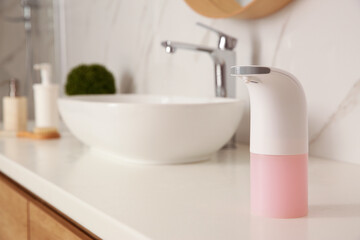 Modern automatic soap dispenser on countertop in bathroom. Space for text