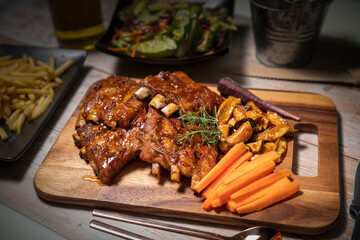 Grilled sliced barbecue pork ribs on wooden plate. Delicious Pork Spare Ribs BBQ seasoned with a...