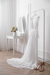Elegant wedding dress hanging on rack indoors