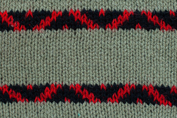 Olive wool knitted canvas with black and red ornament, clouseup 