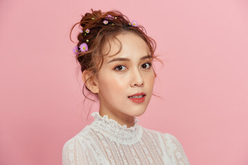 Portrait a close up of the girl in white dress on a pink background. A fair hair, is collected in a beautiful high hairstyle