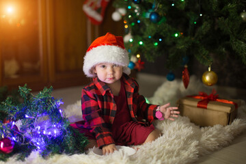 Fototapeta na wymiar a child in red clothes is sitting waiting for the new year. the concept of celebrating Christmas at midnight. holiday costume