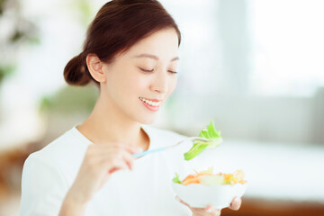 Obraz na płótnie Canvas Young happy woman eating healthy salad at home