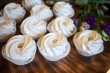 prepared meringues or marshmallows or cupcakes in pastry shop on wooden table