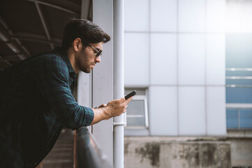 A Caucasian man standing play smartphone at train station.
