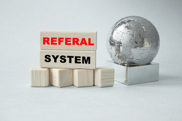 Text REFERAL SYSTEM . Globe and wooden cubes on a gray background. The concept of world business, marketing, finance.