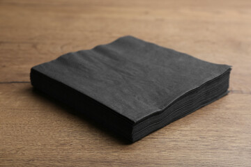 Stack of black clean paper tissues on wooden table