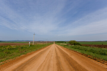 Russian agricultural field. A scenic dirt road passes by agricultural sown fields in Russia.