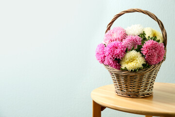 Basket with beautiful asters on table, space for text. Autumn flowers