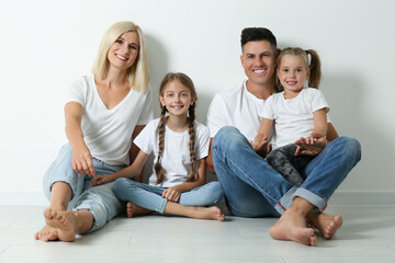 Happy family sitting on floor near white wall