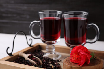 Beautiful Hibiscus flower and delicious tea on wooden tray, closeup