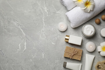 Flat lay composition with towels and skin care products on light grey marble background, space for...