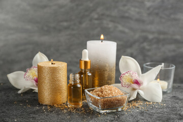 Beautiful spa composition with essential oil, candles and flowers on grey table