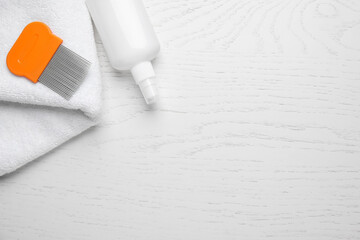 Spray, metal comb and towel for anti lice treatment on white wooden background, flat lay. Space for...