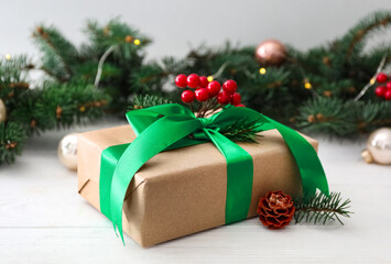 Fototapeta na wymiar Christmas gift box with green bow and festive decor on white wooden table
