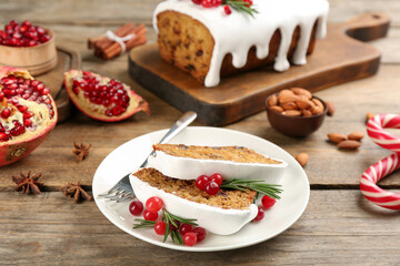 Traditional classic Christmas cake decorated with cranberries, pomegranate and rosemary on wooden table