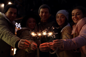 Obraz na płótnie Canvas Group of happy friends with sparklers and champagne at winter fair