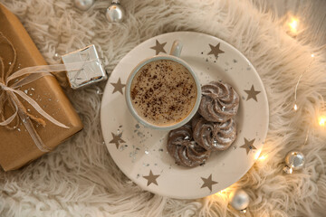 Tasty hot drink, cookies, gift and Christmas lights on fur, flat lay