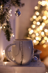 Cup of tasty hot drink and Christmas tree branch indoors. Space for text