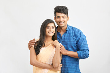 Cheerful Indian young couple in traditional outfit against white.