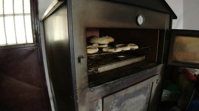 Woman placing pan with fresella bread in the professional oven. Calabria, italy