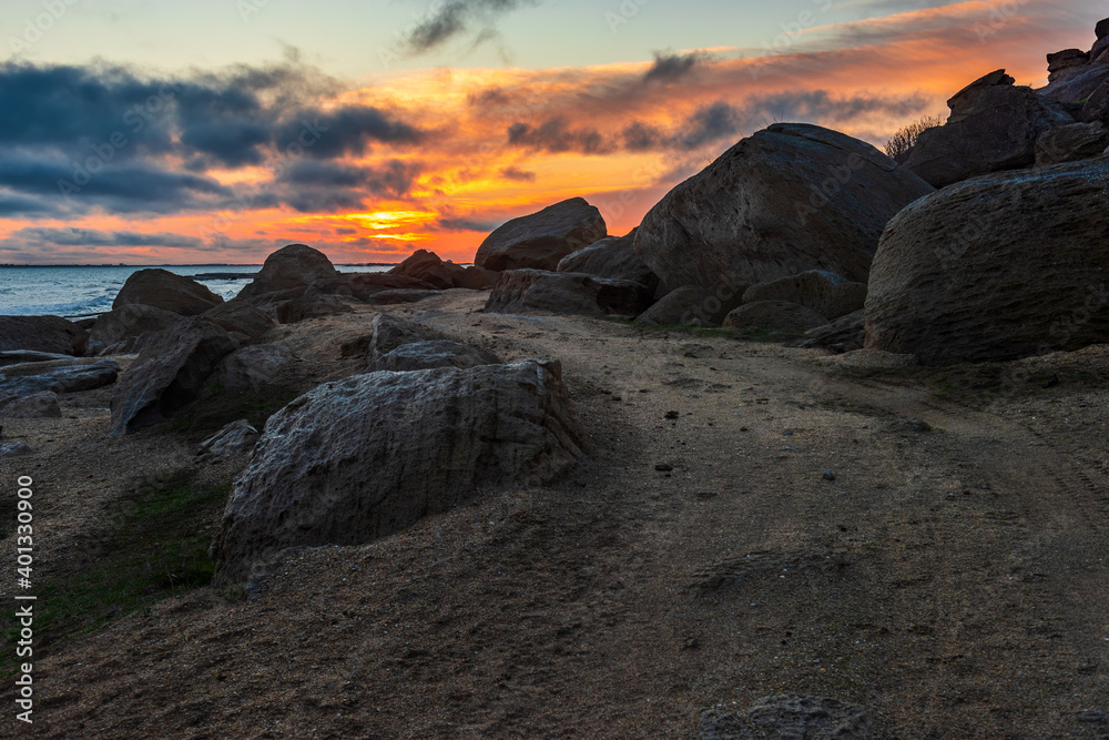 Wall mural Dirt road on rocky shore at colorful sunrise