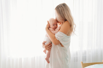 mom with baby standing at the window. after breast-feeding.