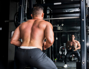 A buff asian male working out at the gym, doing goblet squats. leg and core training workout