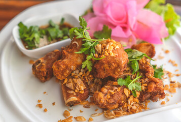 Deep fried spare ribs with garlic on white plate, beautiful food decoration, close up Thailand food menu deep fried spare ribs.