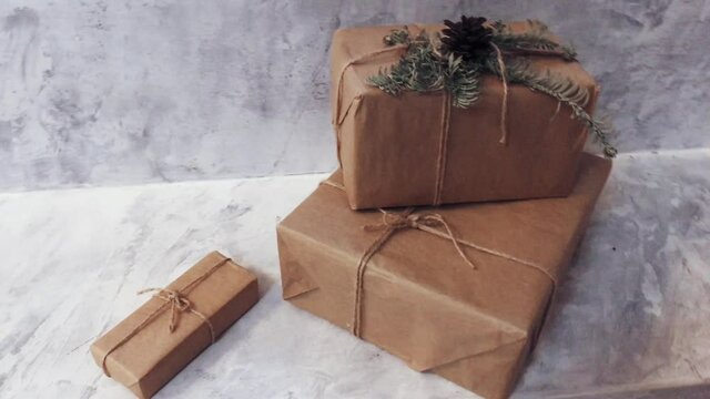 Holiday delivery boxes, parcels wrapped in brown paper, decorated and tied with rough twine, stone background. High quality 4k footage
