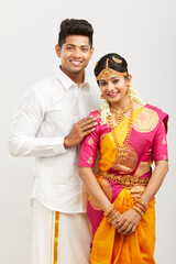 Attractive happy south Indian couple in traditional dress on white.