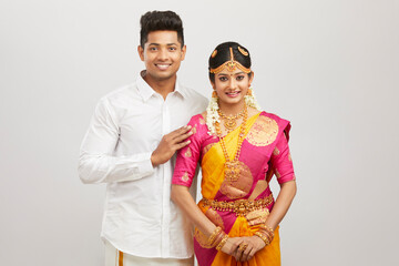 Attractive happy south Indian couple in traditional dress on white.