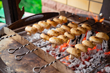 mushrooms are cooked on skewers on coals on the barbecue.