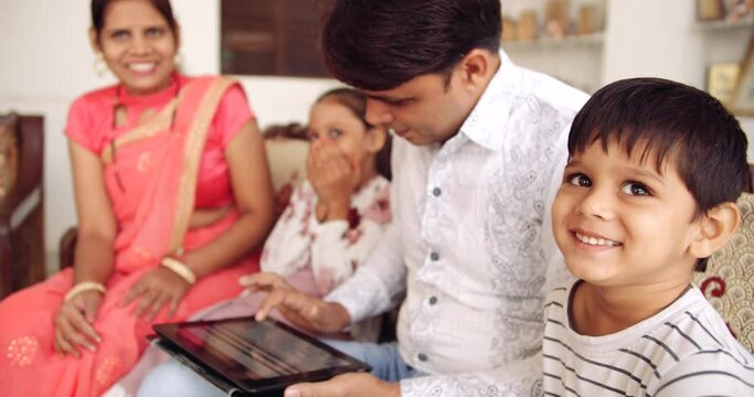 Slow-motion of parents, husband and wife, busy working from home using laptop computer digital technology touchscreen device device while the kids are playing with balloons smiling enjoying