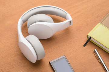 Headphones with note and pen with mp3 players on table.