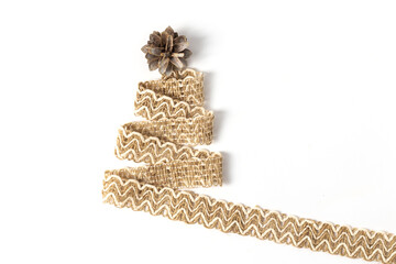 Hemp and flax textile ribbon in the shape of a Christmas tree with a pine cone on the crown. Background for greeting card, poster, banner or invitation for the new 2021 year with copy space.
