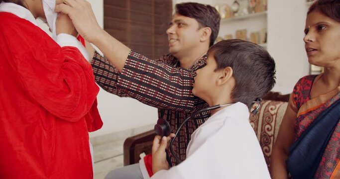 Slow-motion of family getting dressed for Christmas with kids girl wearing Santa Klaus costume hat and the boy is wearing doctor lab coat with stethoscope around his neck