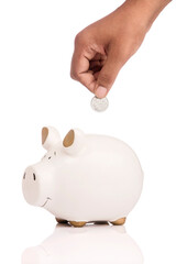Human hand saving coin in piggy banks isolated on white.