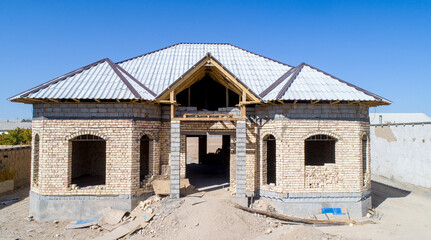 Fototapeta na wymiar Construction of a one-story house. Brick house under construction with a gray tile roof.