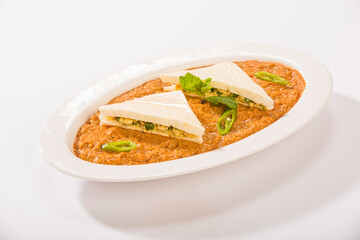 Bowel of cottage gravy with green peas on white.