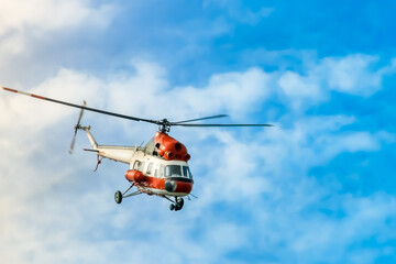 Fototapeta na wymiar red helicopter flying in blue cloudy sky close-up
